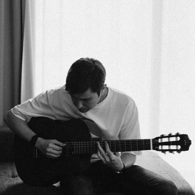 Tim Tikhomirov playing an acoustic guitar